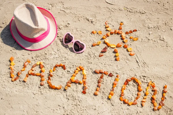 Vacanza di parola con forma di occhiali da sole e cappello di paglia sulla sabbia in spiaggia — Foto Stock