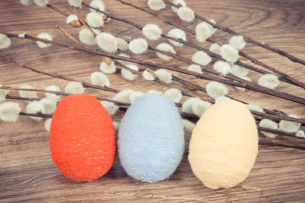 Vintage photo, Twigs of willow and colorful Easter eggs wrapped woolen string on rustic board — Stock Photo, Image