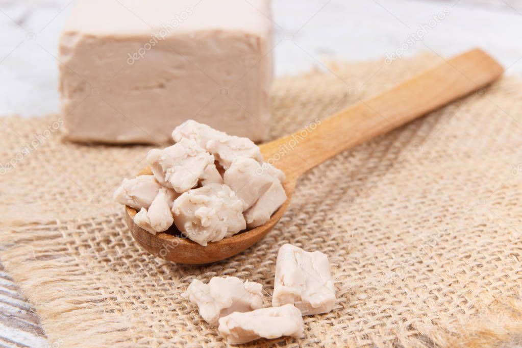 Fresh crumbled yeast on spoon for baking different dough or bread