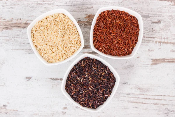 Černé, červené a hnědé rýže v miskách, zdravé bezlepkové potraviny koncept — Stock fotografie