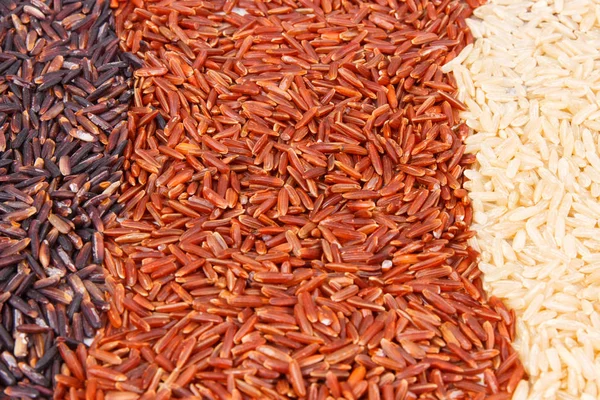 Montón de arroz integral, rojo y negro como fondo, concepto de nutrición saludable — Foto de Stock