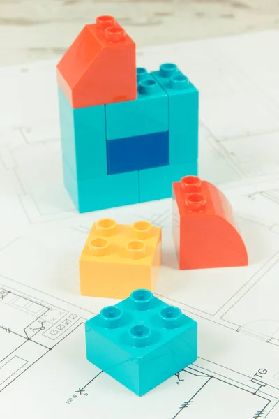 Home shape made of plastic toy blocks and construction diagrams of house — Stock Photo, Image