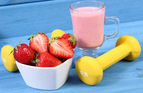 Fresh strawberries, delicious milkshake and dumbbells for fitness, healthy and sporty lifestyle — Stock Photo, Image