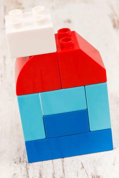 Rustik tahta üzerinde plastik oyuncak blokları yapılmış ev şekli. Bina veya ev konsepti satın alma — Stok fotoğraf
