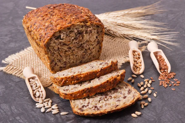 Wholegrain bread with ingredients for baking and ears of rye or wheat grain — Stock Photo, Image