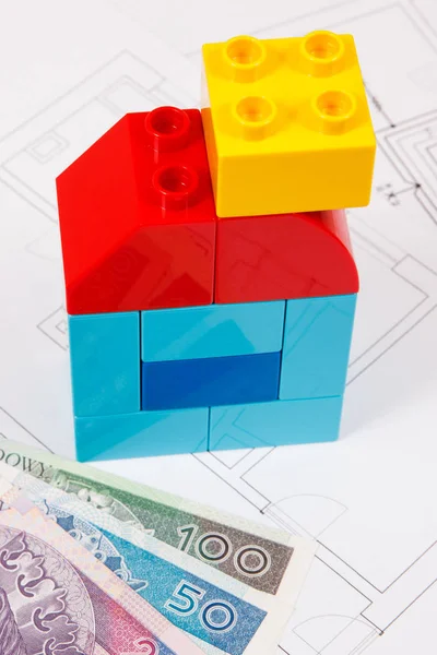 Home shape made of plastic toy blocks, polish currency money and construction diagrams of house — Stock Photo, Image