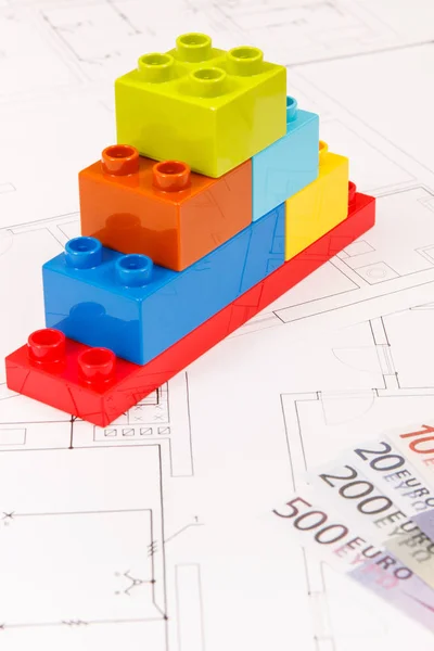 Coloridos bloques de juguetes, monedas euro y plan de vivienda de construcción. Concepto de construcción, compra o alquiler de viviendas — Foto de Stock
