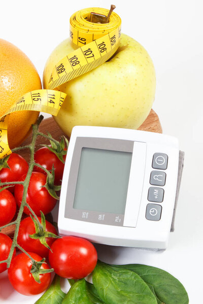 Монитор артериального давления, фрукты с овощами и сантиметром, здоровый образ жизни
