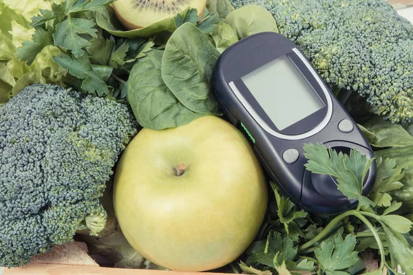 Glucometer for measuring sugar level and green fruits with vegetables. Diabetes, dieting and body detox concept
