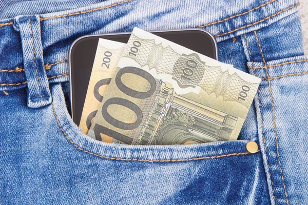 Devises euro et smartphone dans la poche du jean. Concept de paiement sans espèces ou en espèces — Photo
