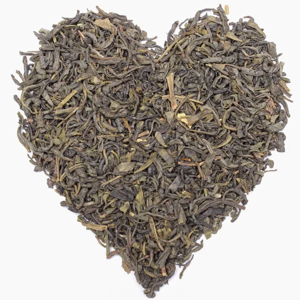 Torkat grönt te i form av hjärta på vit bakgrund. Hälsosamma livsstilar — Stockfoto