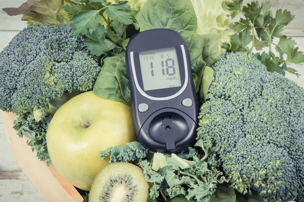 Glucometer for measuring sugar level and green fruits with vegetables. Diabetes, dieting and body detox concept