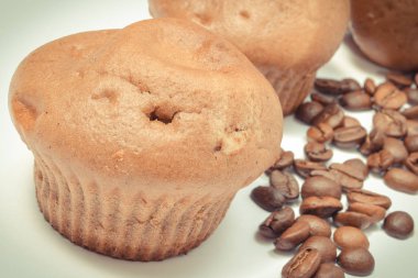 Beyaz arka planda taze pişmiş kekler ve kahve taneleri. Lezzetli tatlı