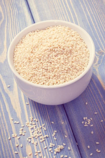 Vintage photo, Heap of sesame seeds in white bowl on wooden boards — Stock Photo, Image