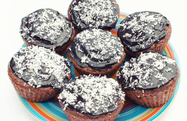 Fresh baked chocolate muffin with desiccated coconut on colorful plate. Delicious dessert — Stock Photo, Image