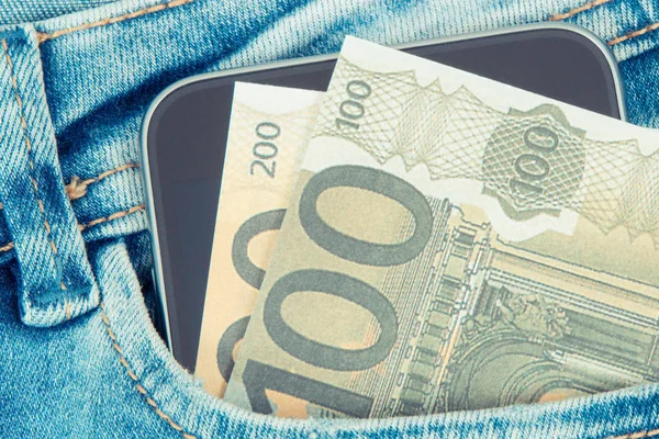 Pieniądze z telefonu komórkowego w kieszeni dżinsy. Płatność bezgotówkowa lub gotówka za koncepcję zakupów — Zdjęcie stockowe