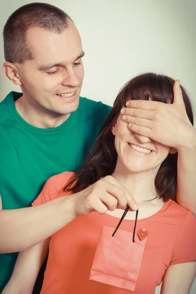 Homem amoroso e sorridente cobrindo olhos surpreendeu a mulher e dando presente para aniversário ou outra celebração — Fotografia de Stock