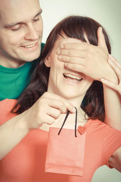 Liebevoller und lächelnder Mann, der die Augen verdeckt, überrascht Frau und schenkt Geschenk für Geburtstag oder andere Feier — Stockfoto