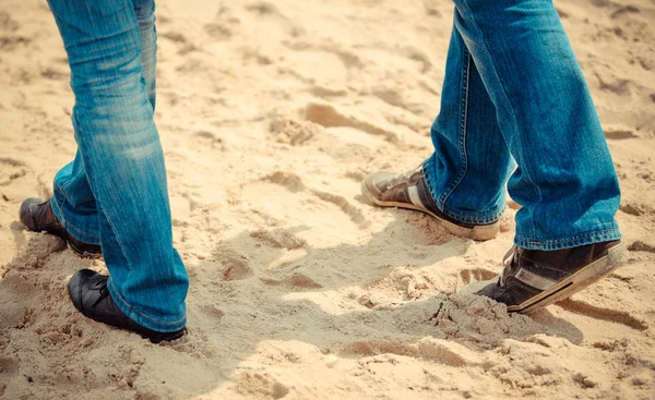 Las piernas de la mujer y el hombre en la arena en la playa. Concepto de verano y vacaciones —  Fotos de Stock