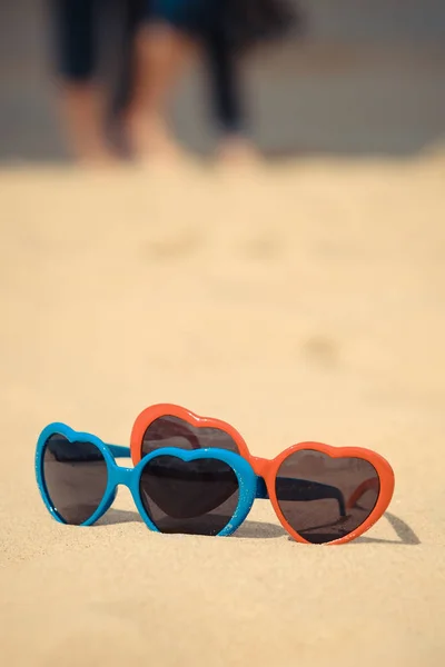 Occhiali da sole azzurri e rossi in forma di cuore su sabbia a spiaggia. Concetto ora legale — Foto Stock