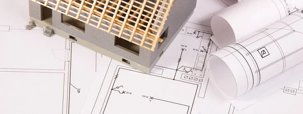 Casa en construcción y rollos de diagramas eléctricos, concepto de casa de construcción — Foto de Stock