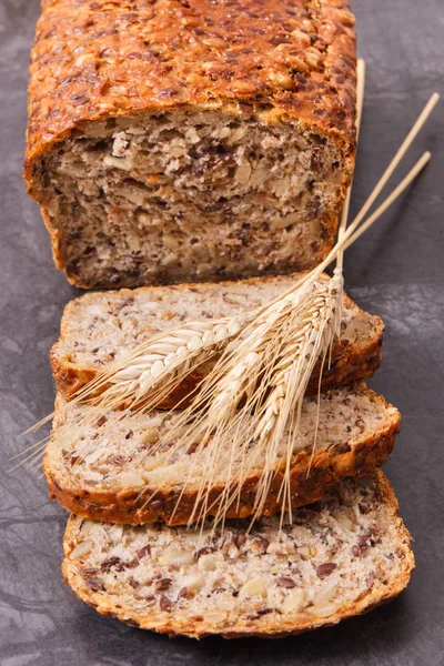 Loaf of wholegrain bread for breakfast and ears of rye or wheat grain — Stock Photo, Image