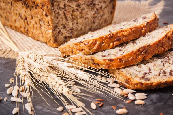 Wholegrain bread with ingredients for baking and ears of rye or wheat grain — Stock Photo, Image