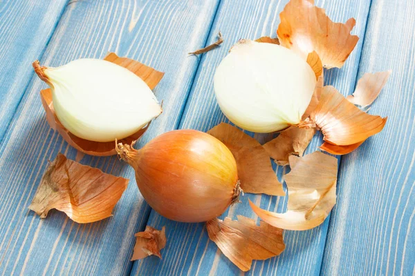 Geschälte frische Zwiebeln liegen auf blauen Brettern, gesundes Ernährungskonzept — Stockfoto