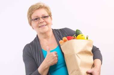 Alışveriş çantası tutarak ve başparmak yukarıya, sağlıklı beslenme Yaşlılıkta gösterilen kadın kıdemli