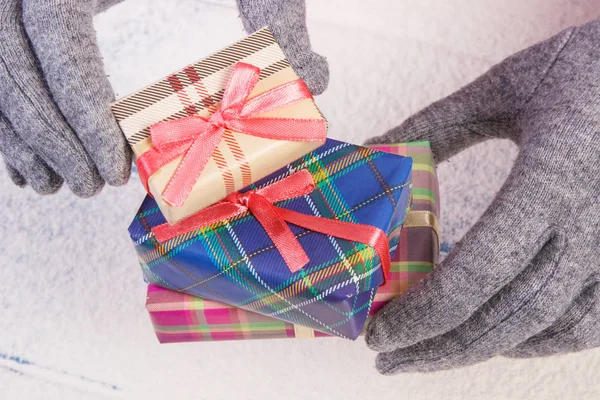 Manos de mujer en guantes de lana con regalo para Navidad u otra celebración — Foto de Stock