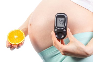 Şeker seviyesi ve turuncu ölçmek için glukometresi olan hamile bir kadın. Hamilelik konsepti sırasında diyabet ve sağlıklı beslenme