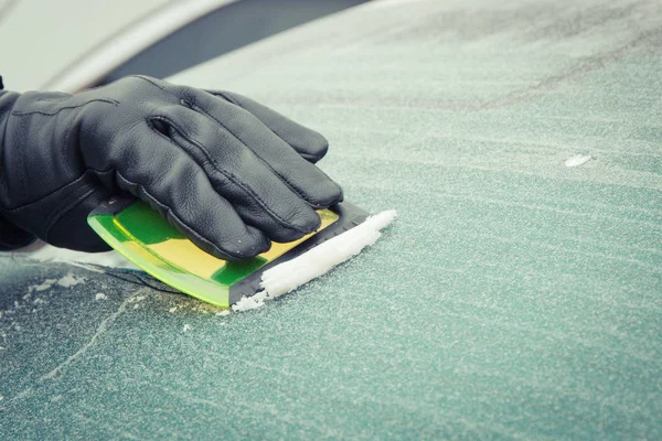 Ruka člověka pomocí škrabadla k odstranění ledu z okna v autě, zimní problémy — Stock fotografie