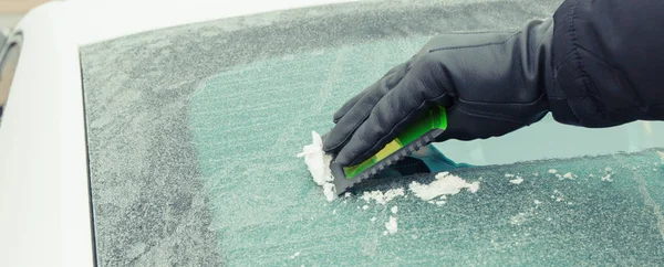 Mão de homem usando raspador para remover o gelo da janela no carro, problemas de inverno — Fotografia de Stock