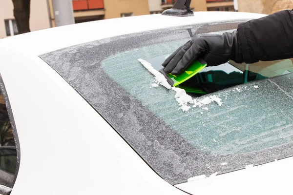 Hand des Mannes mit grünem Kratzer, um Eis aus Autoscheibe zu entfernen, Winterprobleme — Stockfoto