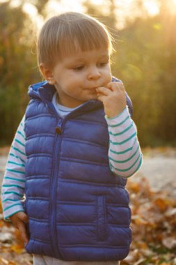 Küçük bebek sonbahar parkında bisküvi ya da kurabiye yiyor.