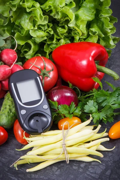 Glucose meter for checking sugar level with vegetables containing minerals and vitamins. Best food for diabetes, slimming and dieting