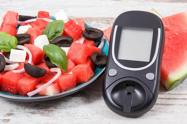 Glucose meter for measuring sugar level and fresh salad of watermelon with feta cheese as source healthy minerals