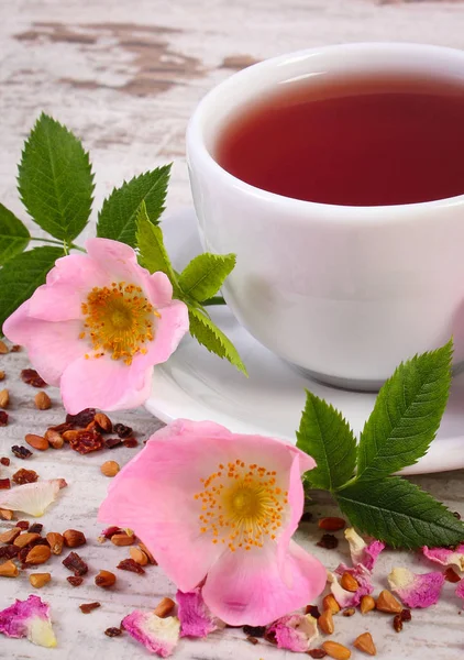 Tasse Tee mit wilder Rosenblüte auf altem rustikalem Holzhintergrund — Stockfoto