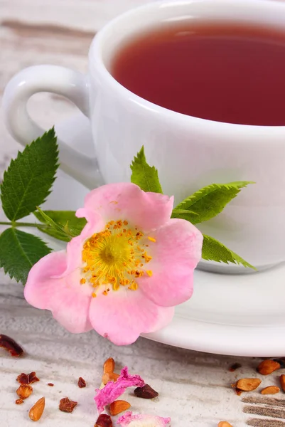 Xícara de chá com flor de rosa selvagem na placa velha — Fotografia de Stock