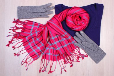 Ahşap yüzey tahtasında kadın kıyafetleri, eldivenler, kazak ve şal ya da eşarp, sonbahar ya da kış için kalın giysiler