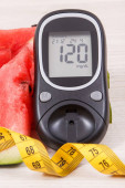 Görögdinnye, glükózmérő a cukorszint és a szalagmérés eredményével, az egészséges életmód fogalma, táplálkozás és fogyás