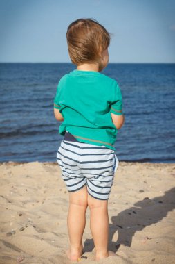 Bebek yaz plajında deniz seyrediyor. Tatil ve çocuk gelişimi kavramı