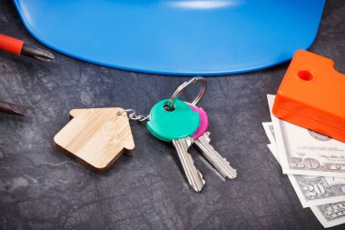 Ev anahtarları, para birimleri doları ve mühendislik işleri için kullanılan iş aletleri. Ev yapma ya da satın alma konsepti. Teknoloji