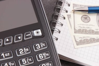 Nakitsiz ödeme işlemleri için kredi kartı okuyucusu, notlar ve dolar yazmak için not defteri. Finans ve iş konsepti