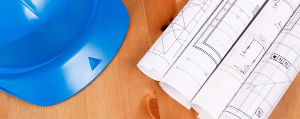 図や電気工事図面のロールとエンジニアの仕事 技術コンセプトのための保護ブルーヘルメット — ストック写真