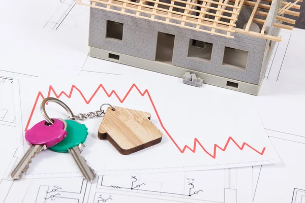 家の電気建設図上のホーム形状と下向きのグラフを持つキー 不動産危機 建設中の小さな家 — ストック写真