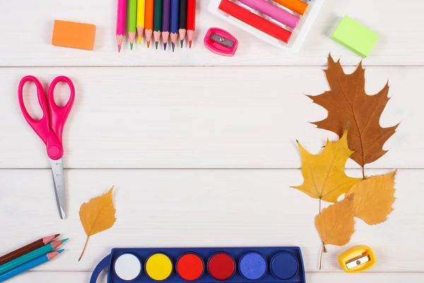 Frame of office accessories and orange leaves on white boards, copy space for text or inscription, back to school in autumn concept