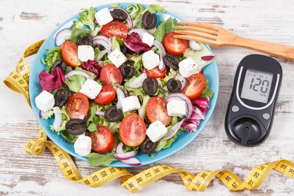 Glucometer with result of sugar level, cintimeter and fresh greek salad with feta cheese and vegetables. Best healthy food for diabetics, dieting and slimming