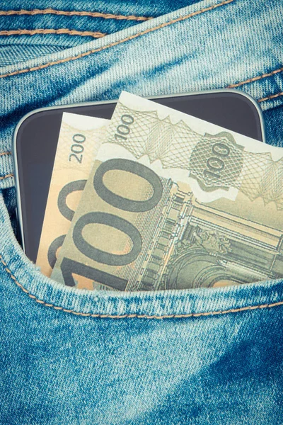 通貨ユーロと青いジーンズのポケットに現金払いのための携帯電話 銀行の概念 — ストック写真