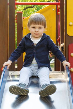 Küçük bebek yaz parkında oyun parkında kaydırağında oynuyor. Çocuk gelişimi kavramı